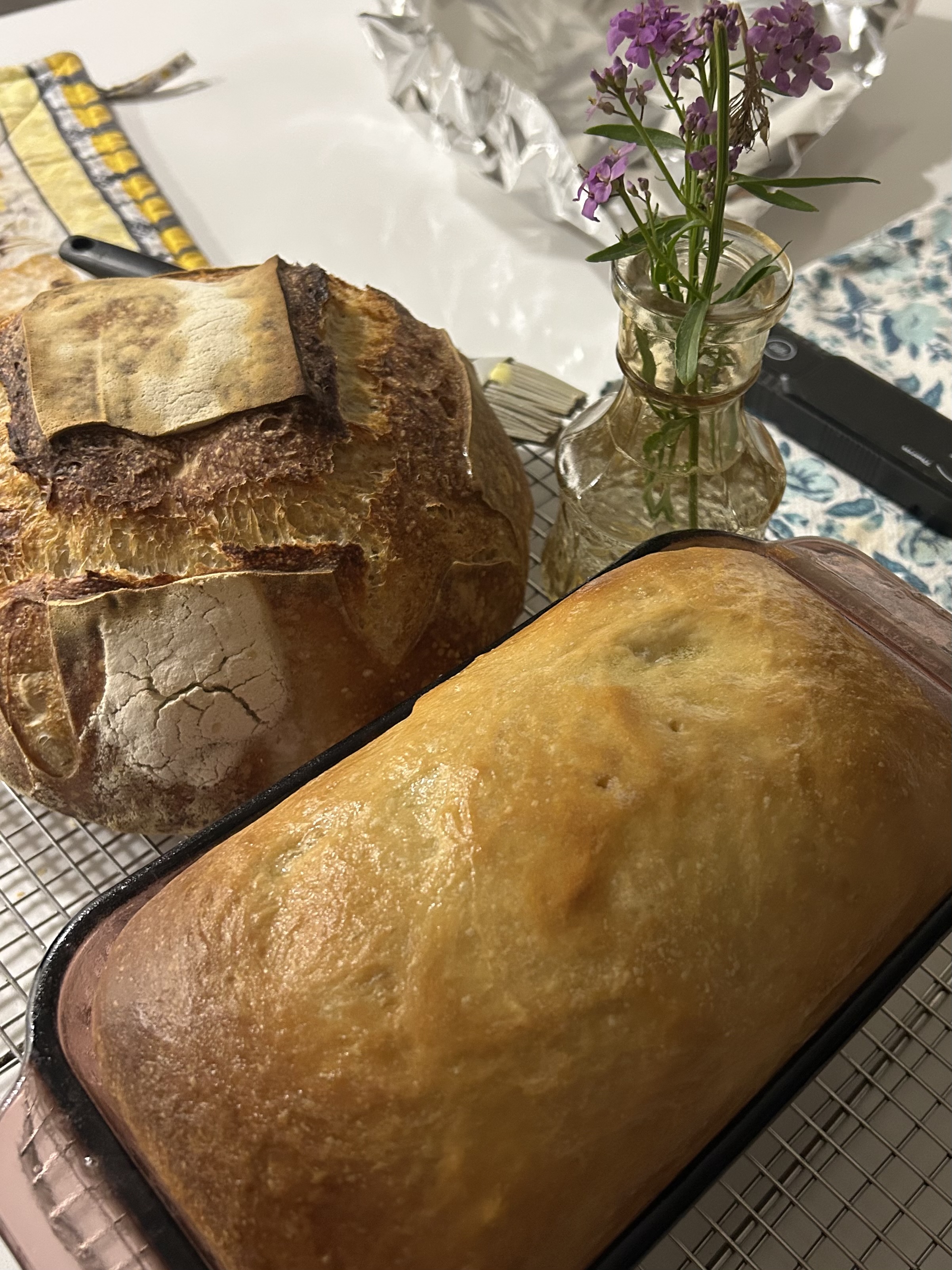 Fresh homemade sandwich bread cooling beside a loaf of rustic bread